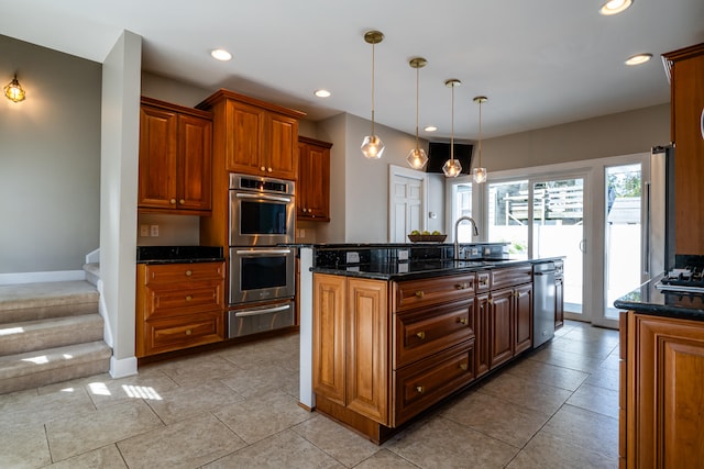 kitchen featuring pendant lighting, dark stone counters, appliances with stainless steel finishes, a center island with sink, and light tile patterned floors