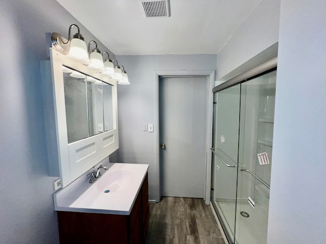 bathroom featuring vanity, hardwood / wood-style floors, and a shower with shower door