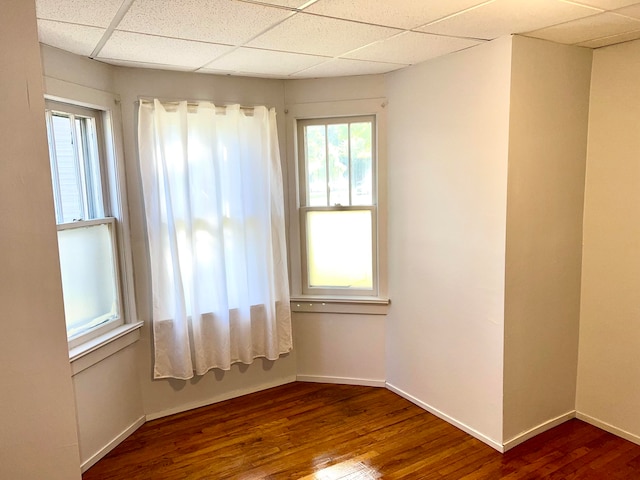 spare room featuring a drop ceiling and hardwood / wood-style flooring