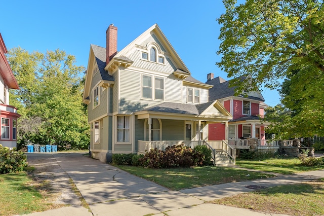 victorian house featuring a porch and a front lawn