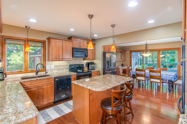 kitchen with a wealth of natural light, a center island, sink, and black appliances