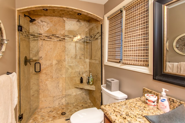 bathroom with a shower with door, vanity, and toilet