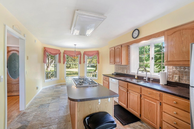 kitchen with dishwasher, sink, hanging light fixtures, decorative backsplash, and light hardwood / wood-style flooring