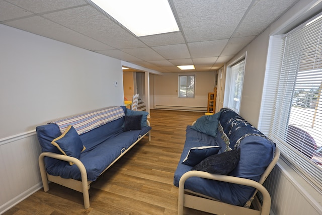 living room featuring baseboard heating, a paneled ceiling, and hardwood / wood-style floors