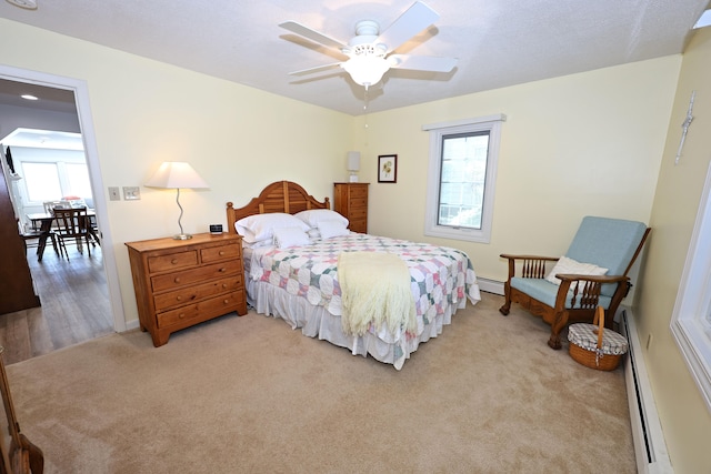 bedroom with ceiling fan, a baseboard radiator, and light carpet