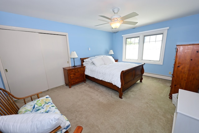 bedroom featuring a closet, light carpet, a baseboard heating unit, and ceiling fan