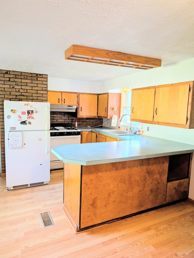 kitchen with a textured ceiling, light hardwood / wood-style floors, kitchen peninsula, and white appliances