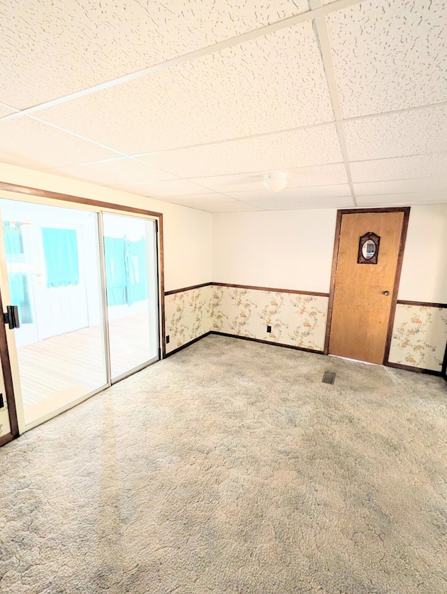 carpeted empty room featuring a drop ceiling