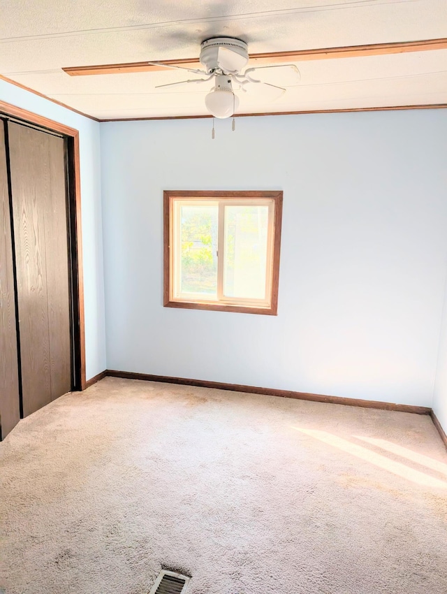 unfurnished bedroom with ceiling fan, a textured ceiling, a closet, and carpet flooring