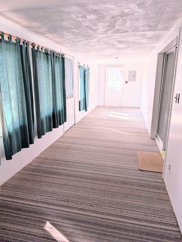 corridor with a textured ceiling and carpet flooring