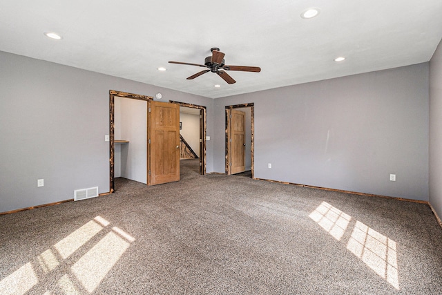 unfurnished bedroom featuring carpet, ceiling fan, a spacious closet, a barn door, and a closet