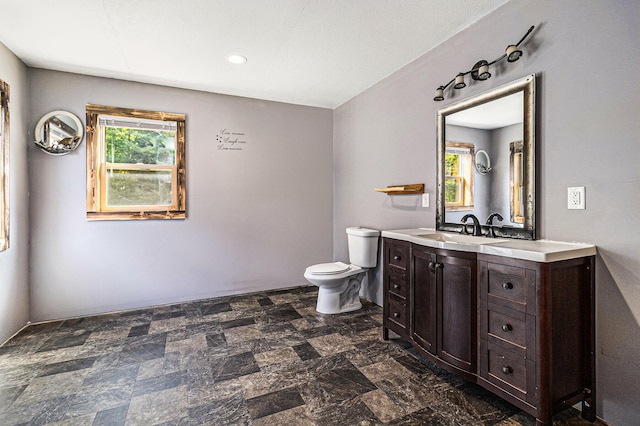 bathroom featuring a wealth of natural light, vanity, and toilet