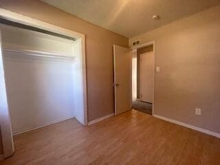 unfurnished bedroom featuring a closet and hardwood / wood-style floors