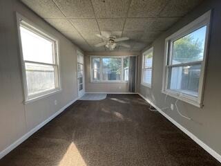 spare room with ceiling fan and dark colored carpet