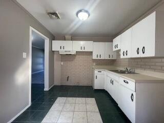 kitchen featuring sink, backsplash, dark tile patterned floors, white cabinets, and range hood