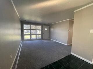 empty room with crown molding and dark carpet