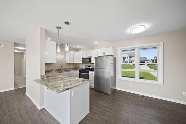 kitchen with dark hardwood / wood-style floors, white cabinets, kitchen peninsula, hanging light fixtures, and appliances with stainless steel finishes