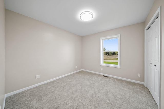 unfurnished bedroom featuring light carpet and a closet