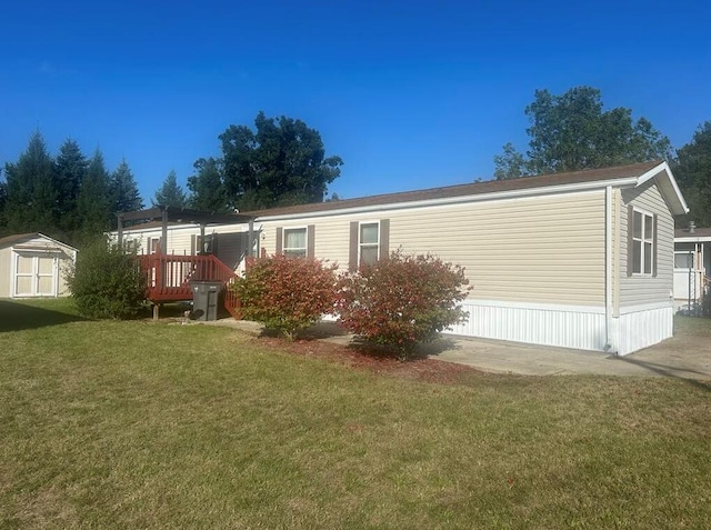 manufactured / mobile home with a wooden deck, a storage shed, and a front yard