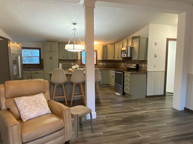 kitchen with tasteful backsplash, a textured ceiling, dark wood-type flooring, pendant lighting, and stainless steel appliances