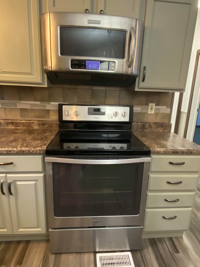 kitchen with stainless steel appliances, dark hardwood / wood-style floors, and tasteful backsplash