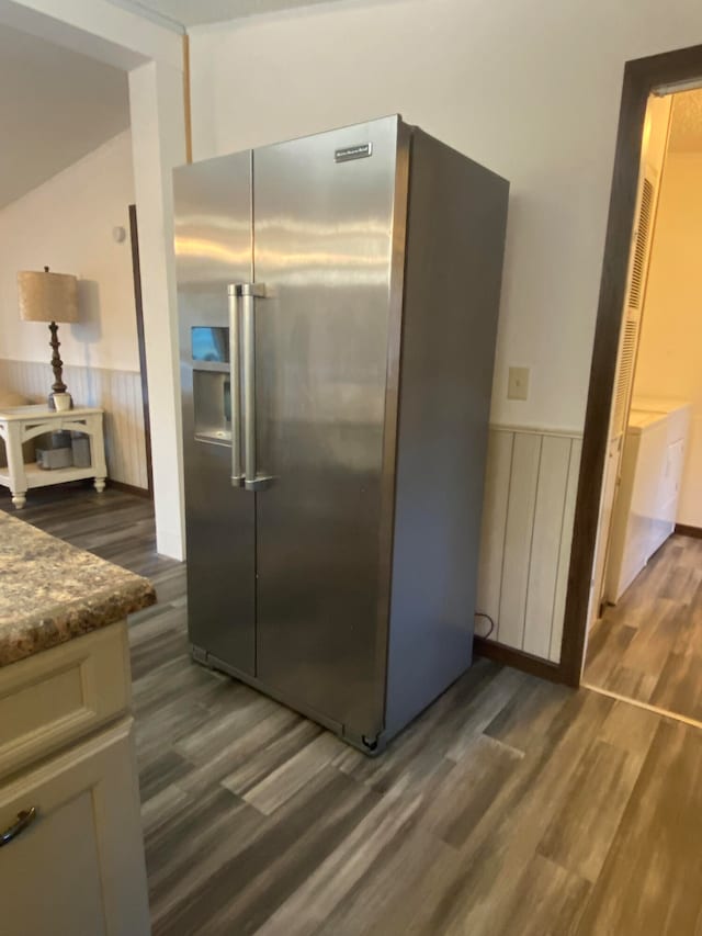 kitchen with dark stone countertops, high quality fridge, and dark hardwood / wood-style flooring