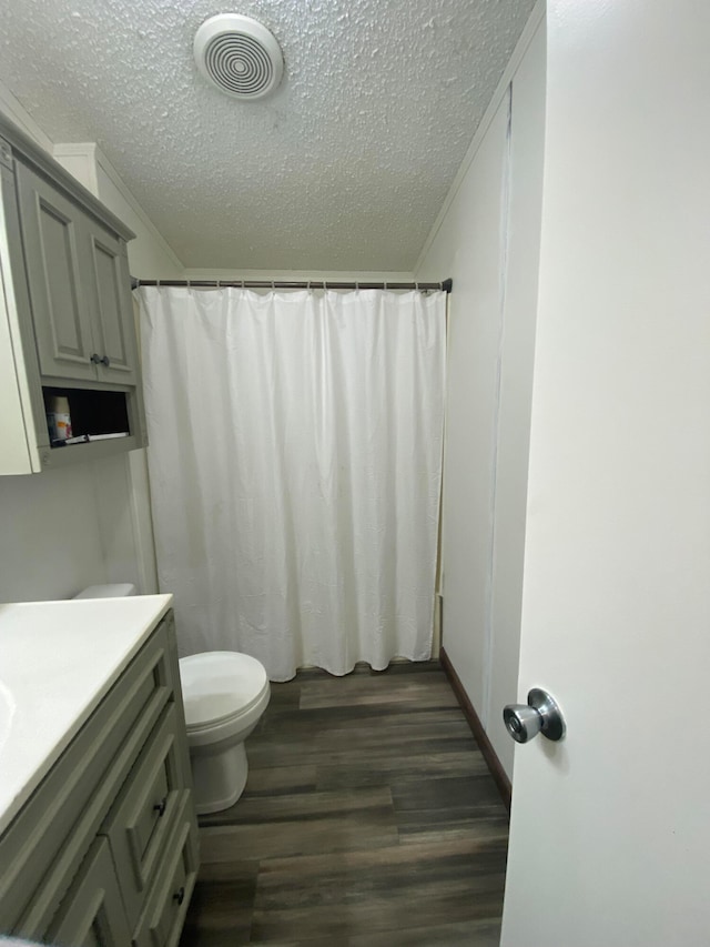 bathroom with hardwood / wood-style flooring, toilet, a shower with curtain, vanity, and a textured ceiling