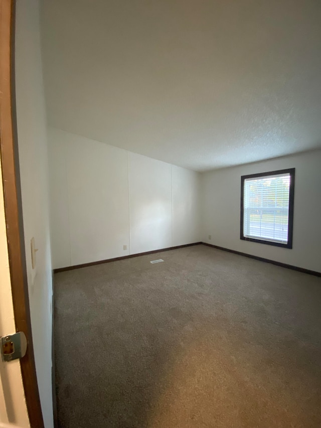 empty room featuring a textured ceiling and dark carpet