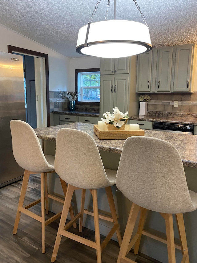 kitchen with hardwood / wood-style floors, a kitchen breakfast bar, a textured ceiling, gray cabinets, and stainless steel appliances