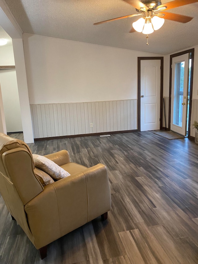 living room featuring dark hardwood / wood-style floors, a textured ceiling, and ceiling fan