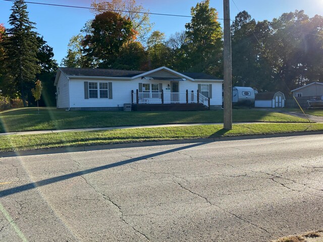 ranch-style house featuring covered porch and a front yard