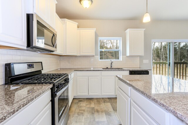 kitchen featuring hanging light fixtures, sink, light hardwood / wood-style flooring, white cabinetry, and appliances with stainless steel finishes