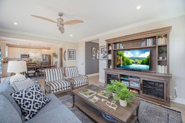 living room featuring ceiling fan, crown molding, and light hardwood / wood-style floors