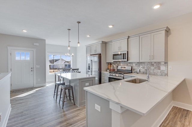 kitchen with sink, a kitchen island, hardwood / wood-style flooring, stainless steel appliances, and a kitchen breakfast bar