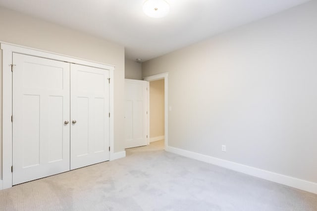 unfurnished bedroom with light carpet and a closet