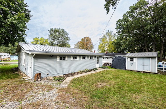 rear view of property with a storage shed and a yard