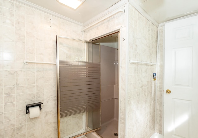 bathroom with a shower with shower door and ornamental molding