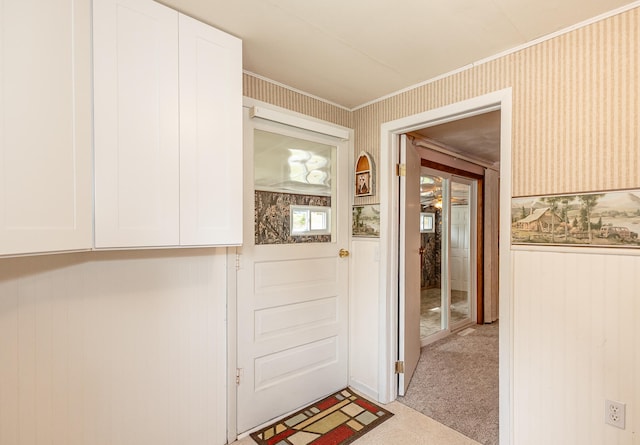 doorway to outside with wooden walls and light carpet