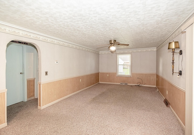 empty room featuring carpet flooring, wood walls, and ceiling fan