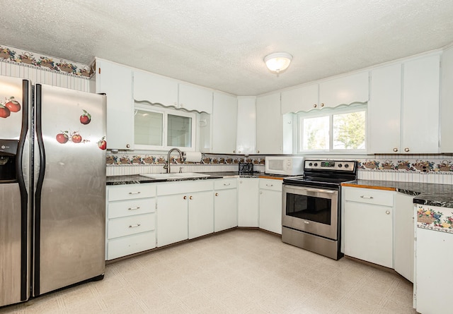 kitchen featuring stainless steel appliances, white cabinets, a textured ceiling, and sink