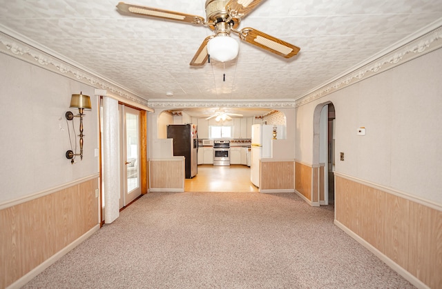 interior space featuring light carpet, wooden walls, and crown molding