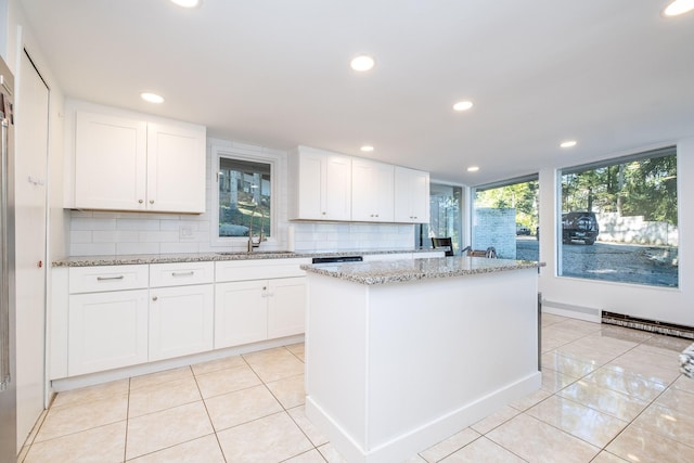 kitchen with a wealth of natural light, tasteful backsplash, a kitchen island, and white cabinets