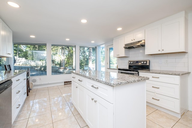 kitchen featuring light stone counters, a center island, white cabinets, stainless steel appliances, and light tile patterned floors