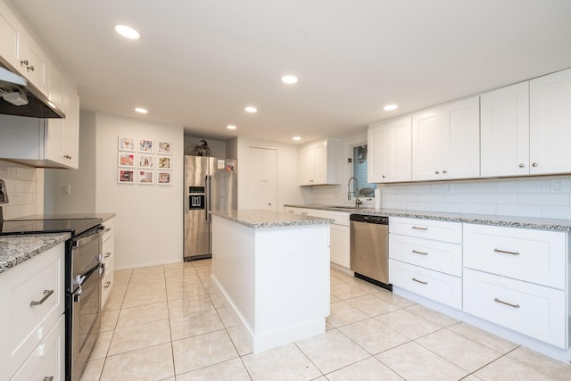 kitchen featuring light stone counters, light tile patterned floors, a kitchen island, white cabinetry, and stainless steel appliances