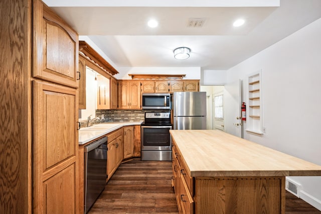 kitchen featuring a kitchen island, dark hardwood / wood-style floors, tasteful backsplash, sink, and appliances with stainless steel finishes