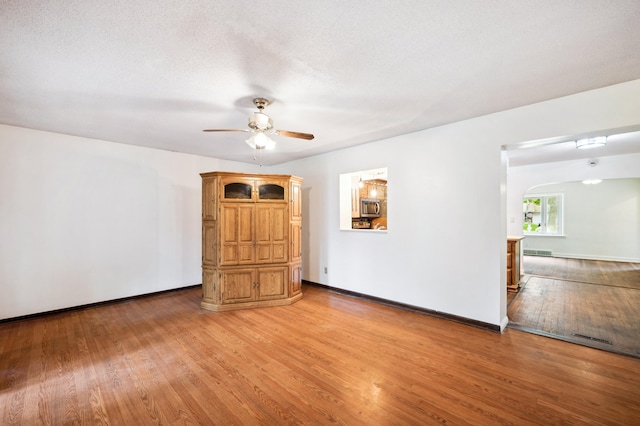 empty room with ceiling fan, a textured ceiling, and light hardwood / wood-style flooring