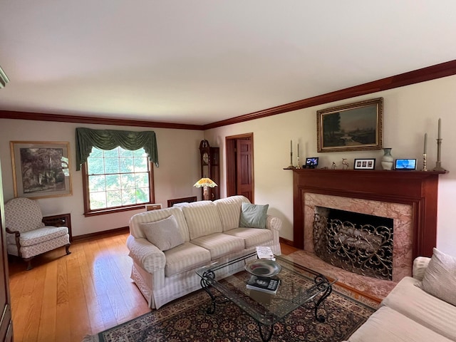 living room with ornamental molding, light wood-type flooring, and a high end fireplace