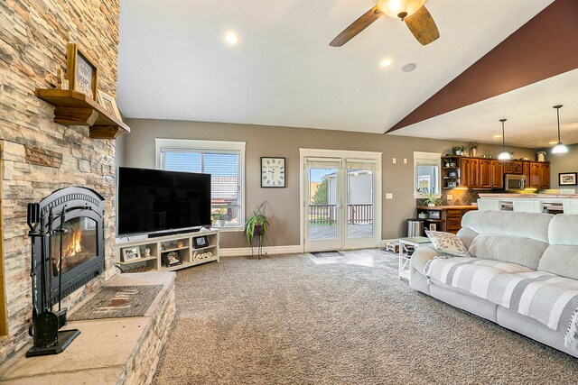 living room featuring a stone fireplace, ceiling fan, light carpet, and high vaulted ceiling