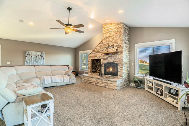 carpeted living room featuring a stone fireplace, lofted ceiling, and ceiling fan