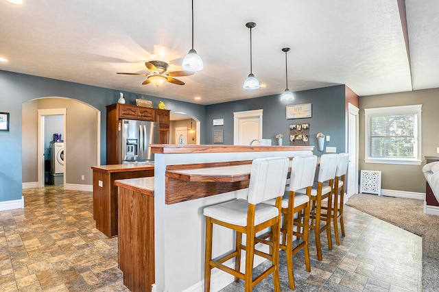 kitchen with a breakfast bar, carpet, decorative light fixtures, ceiling fan, and stainless steel fridge